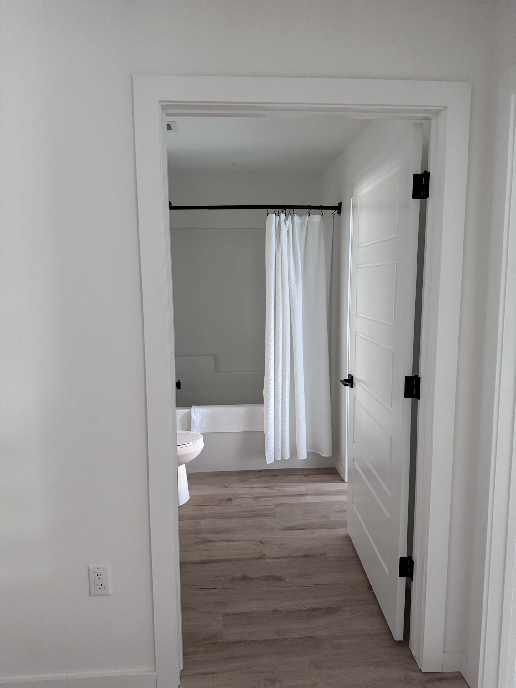 Bathroom entrance finished with a white panel door, casing, and black hardware
