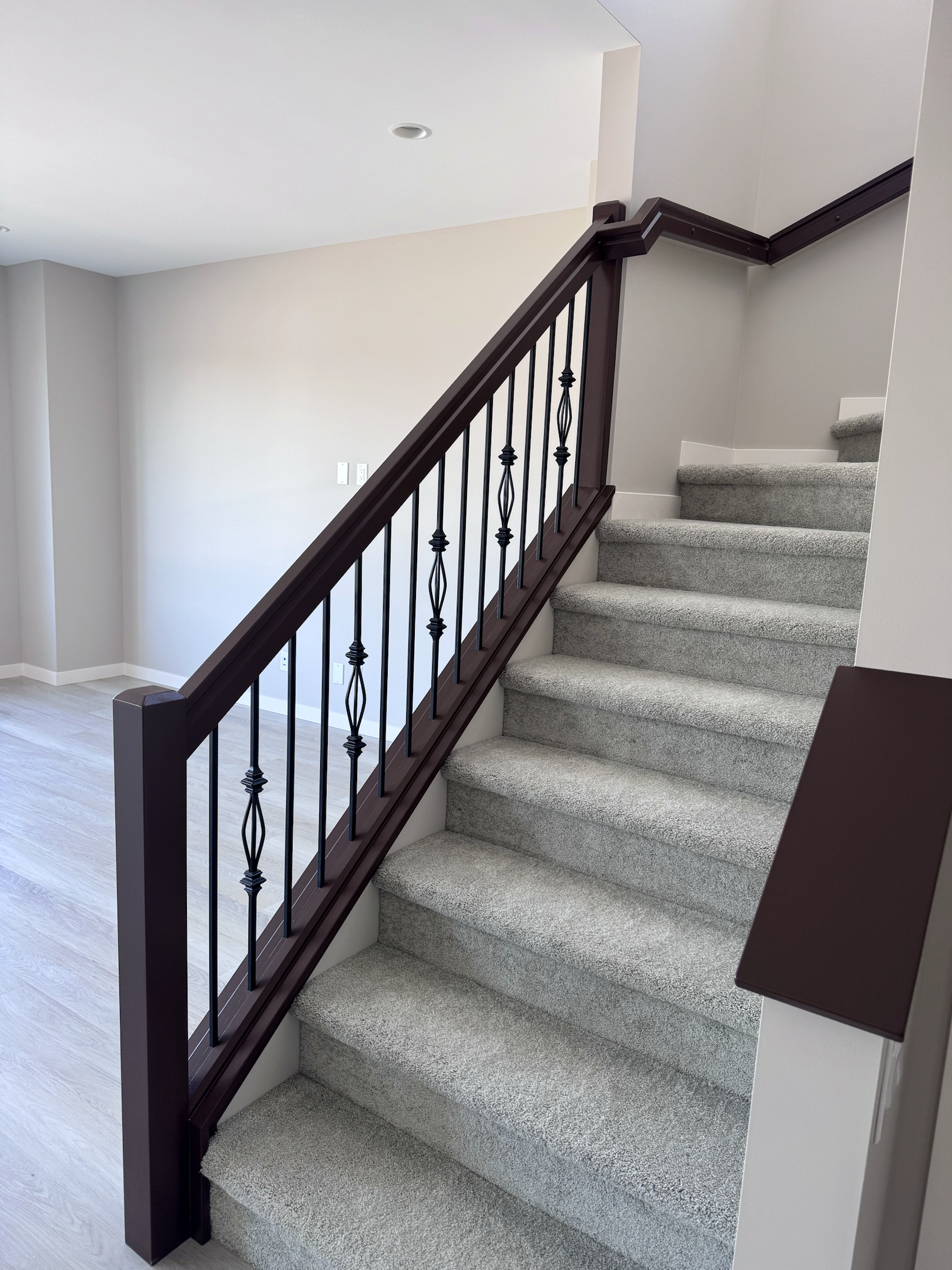 Dark stained stair handrail with decorative black metal balusters