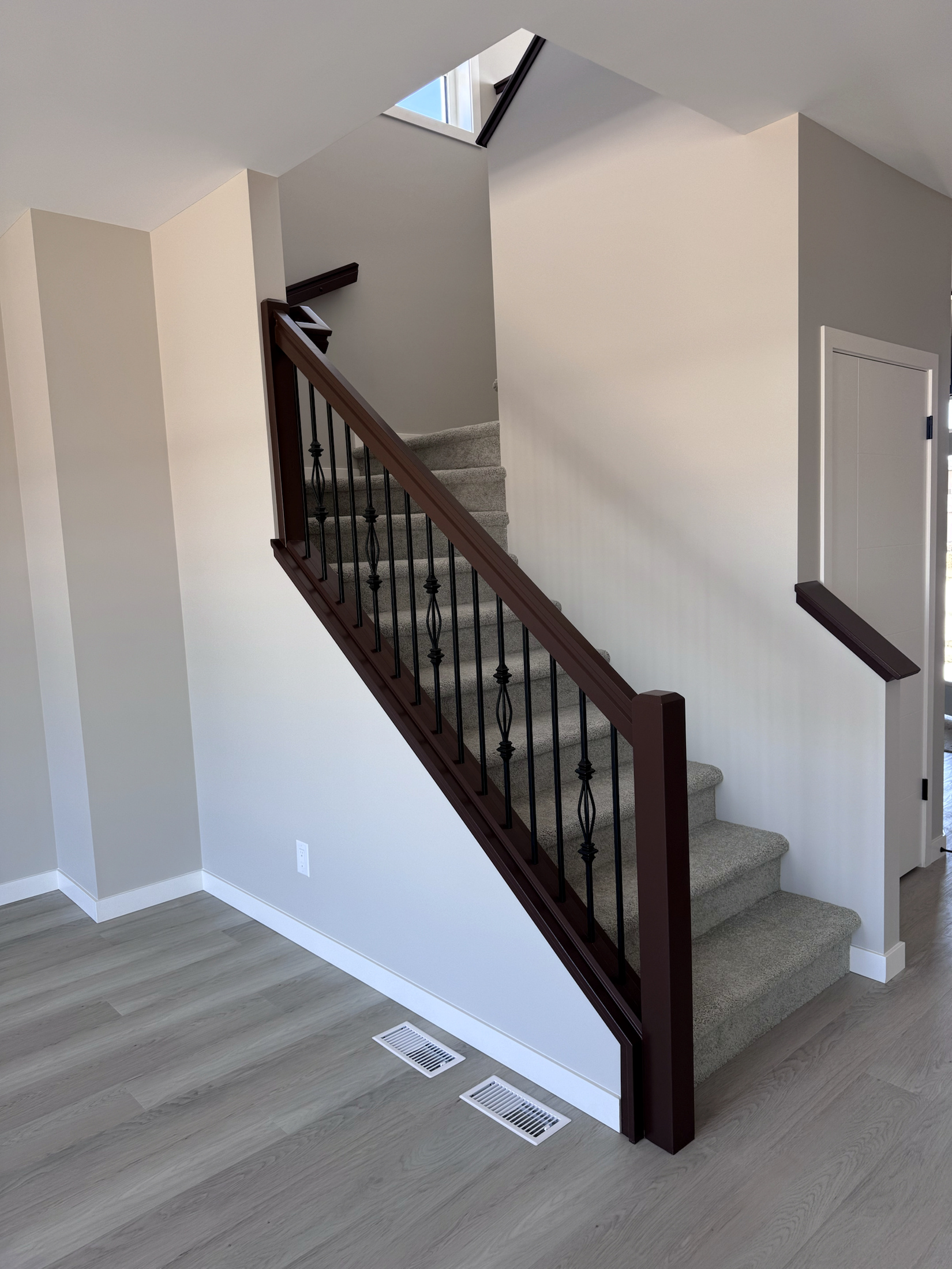 Dark stained stair railing fitted alongside a carpeted staircase