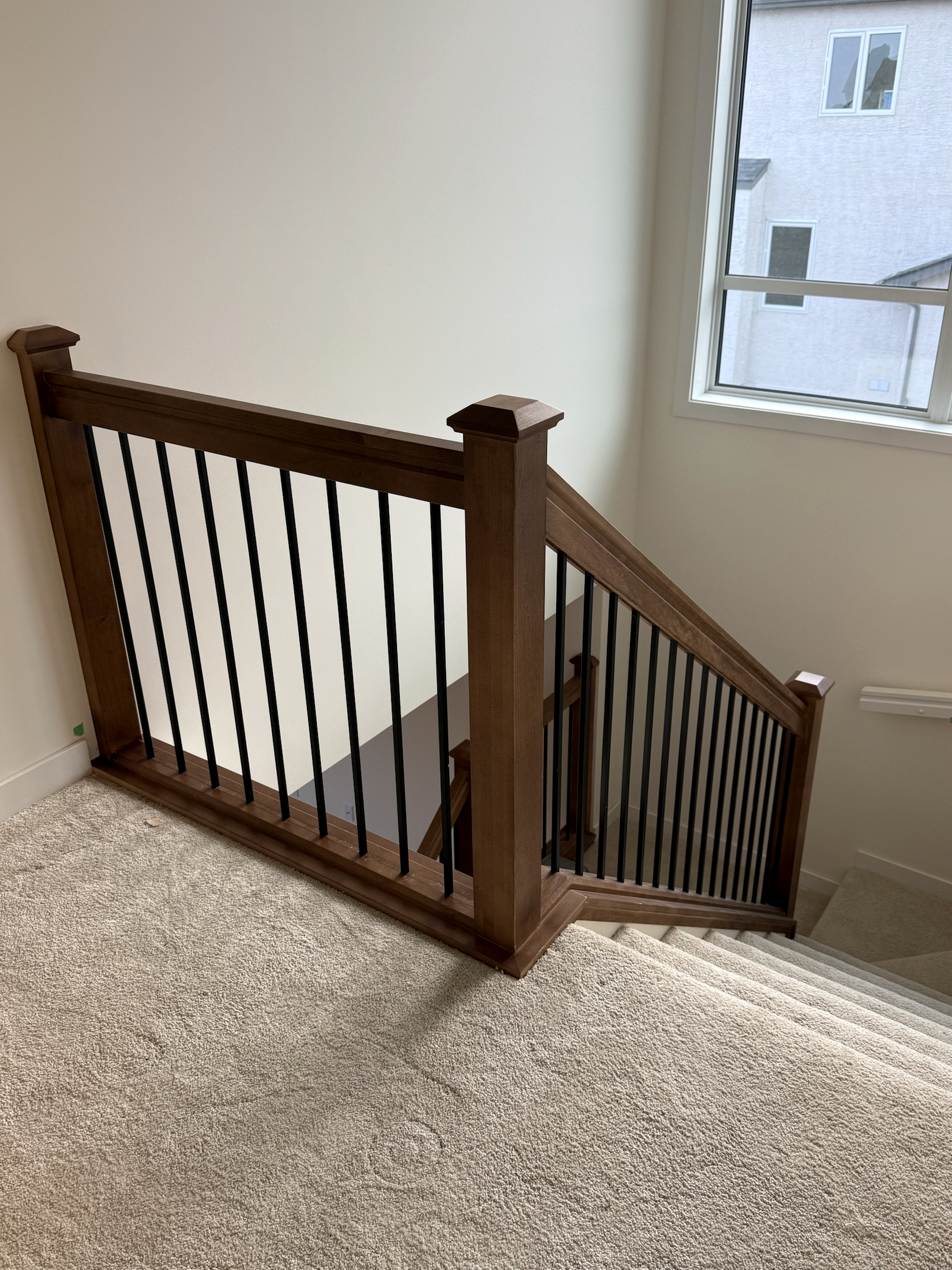Stained newel post and guardrail detail at an upper stair landing