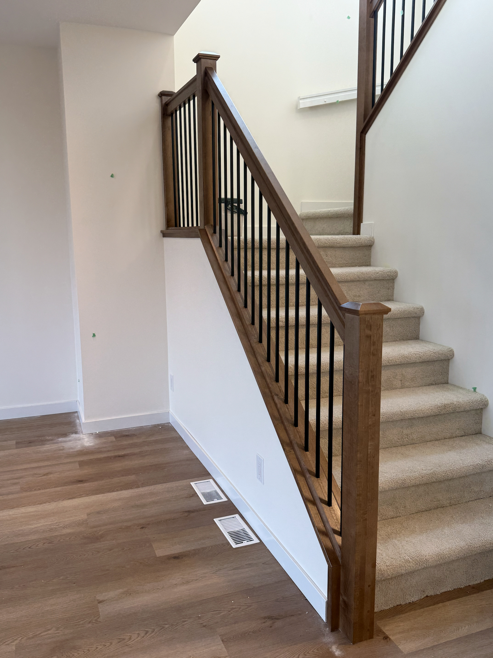 Stained stair railing wrapping a carpeted stair turn